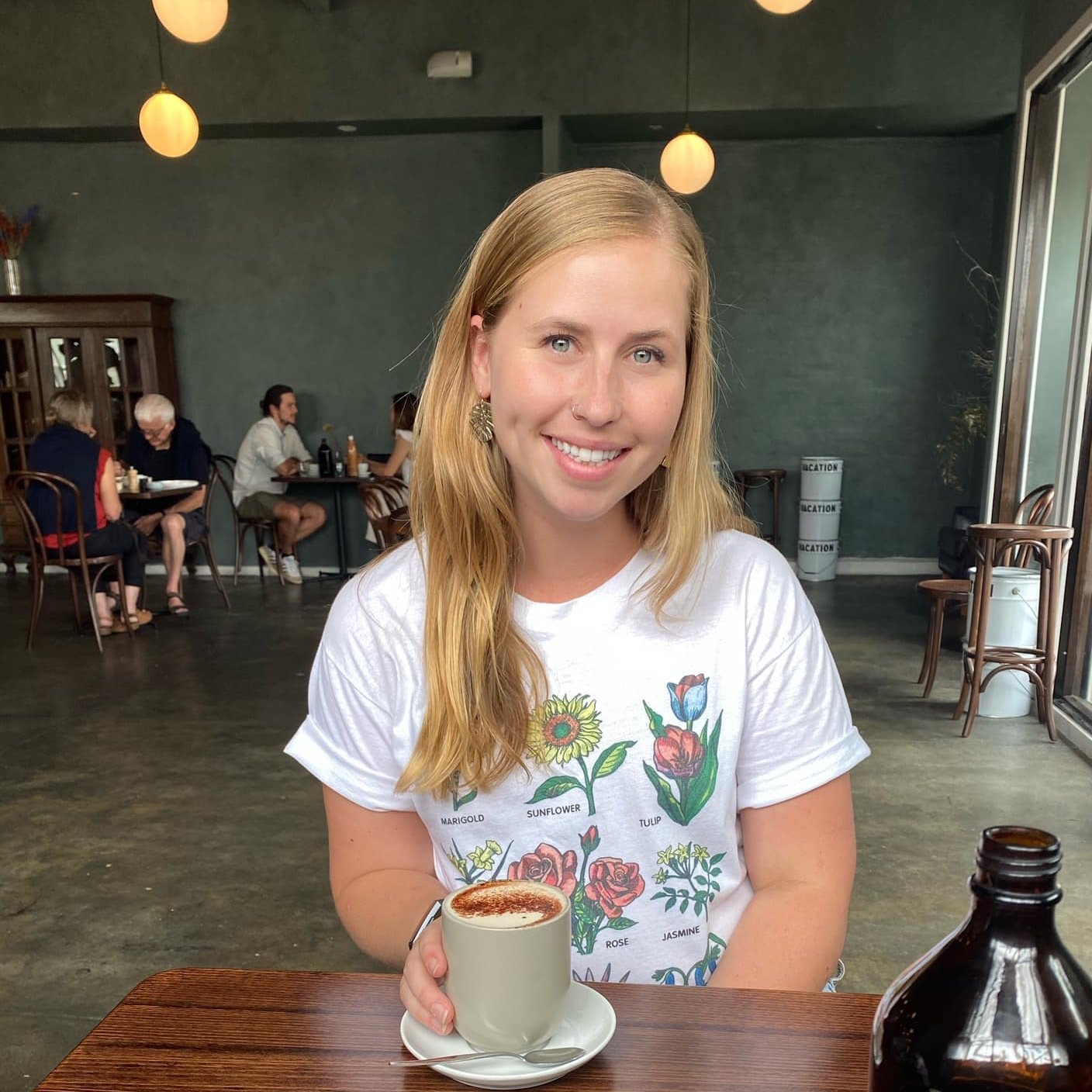 Picture of Catie Strigenz, smiling with coffee